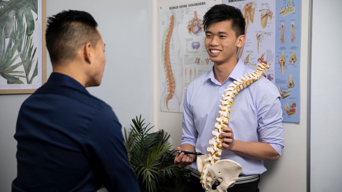 Macquarie Park Physiotherapist Joshua Shum with spine model 1170 x 658